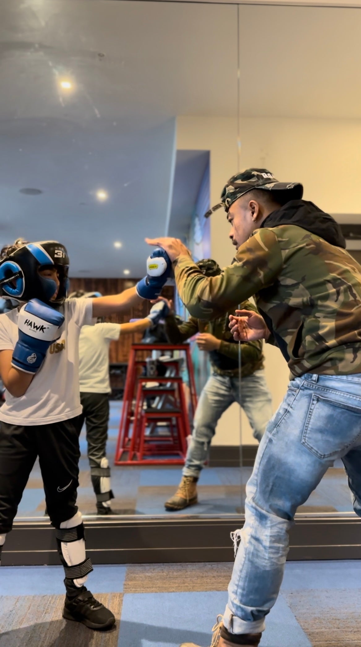 Coach Rada Rann watching a client work the heavy bag during a coached session.