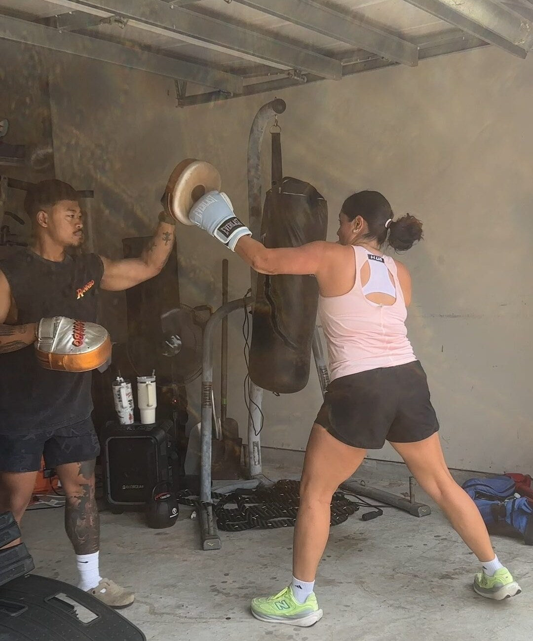 Coach Rada Rann holding focus pads as a client throws a punch during a private session.