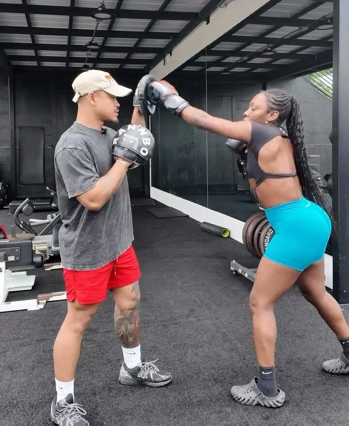 Coach Rada Rann holding RANNBO focus pads as a client throws a jab during a private boxing session.