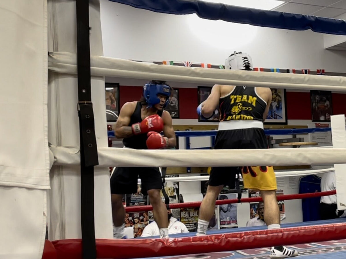 Rada Rann, in blue headgear and red gloves, competing in an amateur boxing bout.